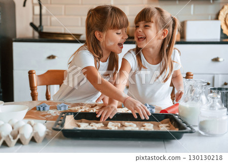 Smiling, playful mood. Two little girls are preparing food on the kitchen with garlands Smiling, playful mood. Two little girls are preparing food on the kitchen with garlands 130130218