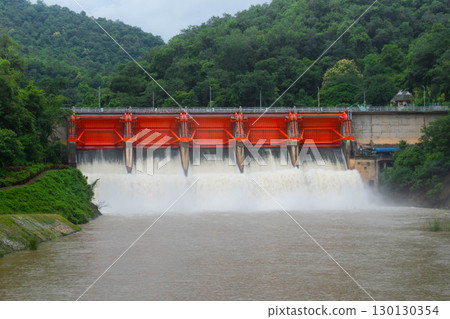 Hydro dam structure with open gates releasing muddy flood water. 130130354