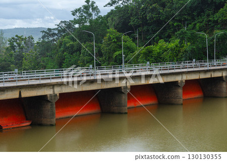 Red floodgate dam structure over muddy river water. 130130355