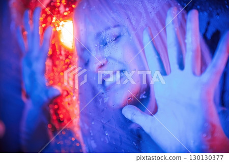 Hands are on the surface. Stylish woman with white hair is behind wet transparent plastic sheet 130130377