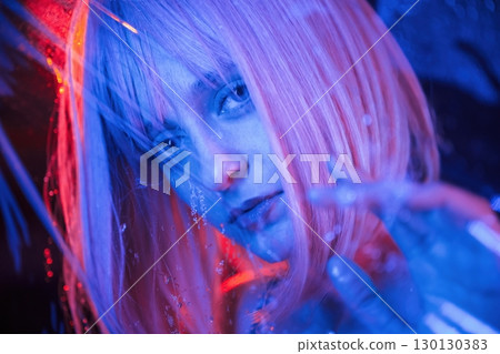Posing for camera. Stylish woman with white hair is behind wet transparent plastic sheet 130130383