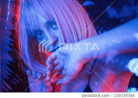 Futuristic style. Stylish woman with white hair is behind wet transparent plastic sheet Futuristic style. Stylish woman with white hair is behind wet transparent plastic sheet 130130388