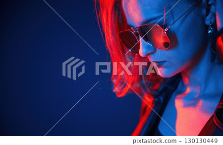 Looks down, side close up view. Cool young woman portrait in neon colors 130130449