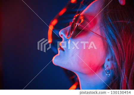 Side view, in eyewear. Cool young woman portrait in neon colors 130130454
