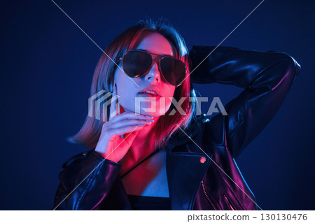Against dark blue background. Cool young woman portrait in neon colors Against dark blue background. Cool young woman portrait in neon colors 130130476
