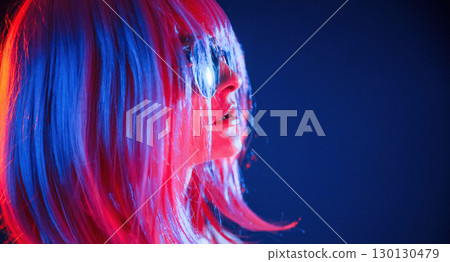 White hair of medium length. Woman is in studio with neon colors 130130479