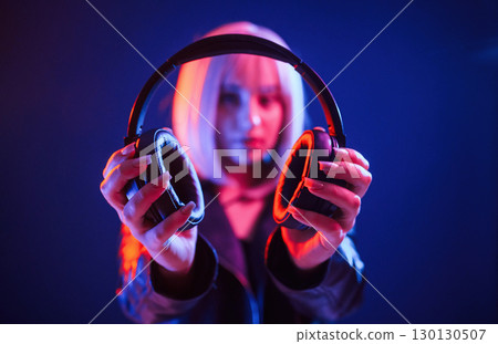 Showing headphones. Woman with white hair is in studio with neon colors 130130507