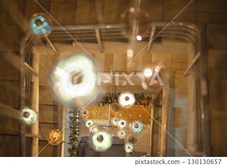 top view of spiral staircase decorated with hanging Christmas lights and holiday garland, soft blur effect with glass orbs in focus, interior design, festive decor, architectural detail top view of spiral staircase decorated with hanging Christmas lights and holiday garland, soft blur effect with glass orbs in focus, interior design, festive decor, architectural detail 130130657