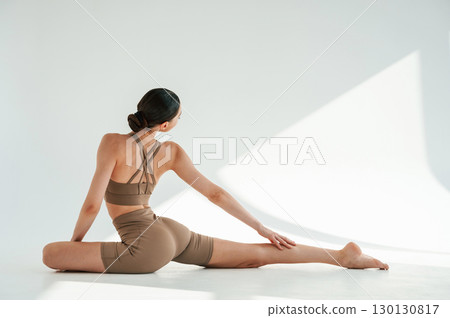 Flexible body. Young woman is doing fitness yoga indoors against white background Flexible body. Young woman is doing fitness yoga indoors against white background 130130817