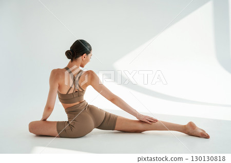 Flexible body. Young woman is doing fitness yoga indoors against white background Flexible body. Young woman is doing fitness yoga indoors against white background 130130818