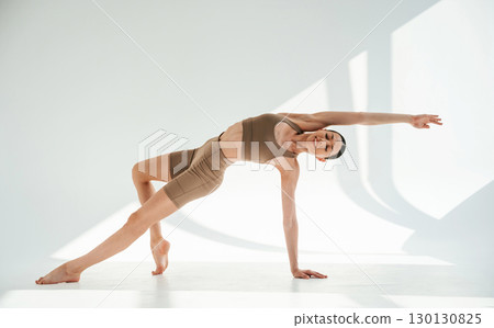 Sporty fitness exercises. Young woman is doing yoga indoors against white background Sporty fitness exercises. Young woman is doing yoga indoors against white background 130130825