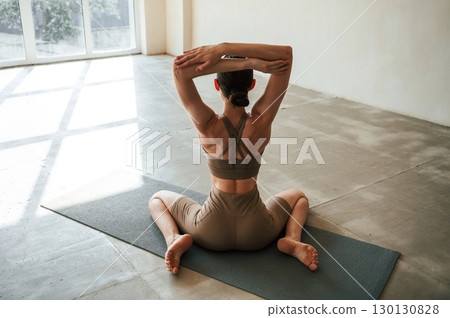 With hands up. Rear view of young woman on yoga mat indoors With hands up. Rear view of young woman on yoga mat indoors 130130828