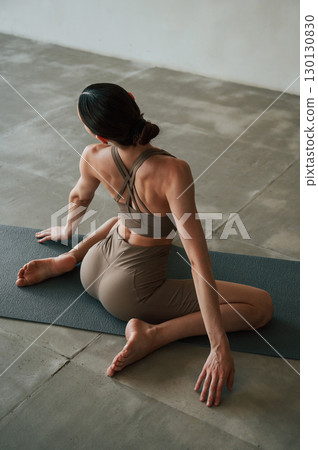 Rear view of young woman on yoga mat indoors 130130830