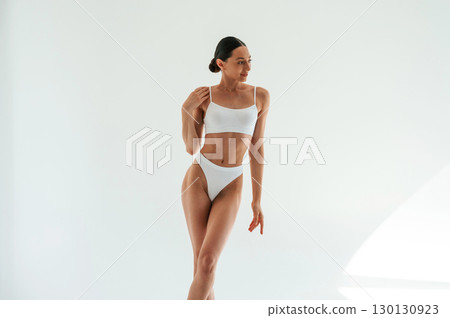 Standing and posing. Woman in white underwear with slim body type against white background Standing and posing. Woman in white underwear with slim body type against white background 130130923