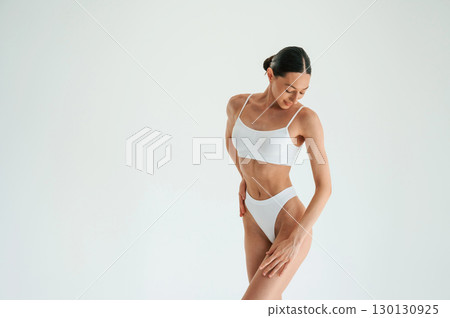 Standing and posing. Woman in white underwear with slim body type against white background Standing and posing. Woman in white underwear with slim body type against white background 130130925