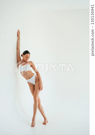 Full height photo. Woman in white underwear with slim body type against white background Full height photo. Woman in white underwear with slim body type against white background 130130941