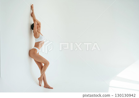 Full height photo. Woman in white underwear with slim body type against white background Full height photo. Woman in white underwear with slim body type against white background 130130942