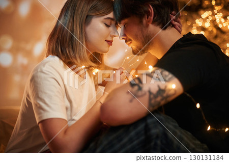 Conception of love. Beautiful young couple indoors, celebrating new year against projector Conception of love. Beautiful young couple indoors, celebrating new year against projector 130131184