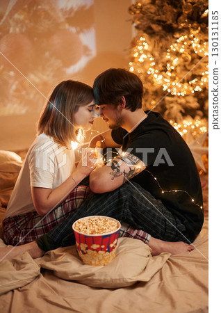 Conception of love. Beautiful young couple indoors, celebrating new year against projector Conception of love. Beautiful young couple indoors, celebrating new year against projector 130131185