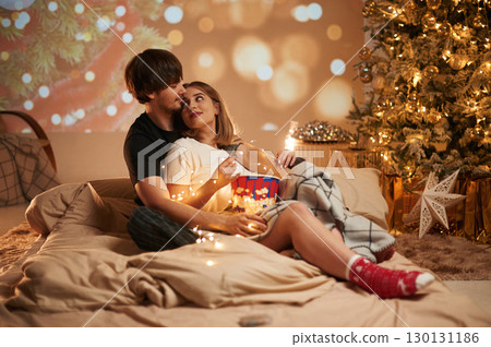 With pizza. Beautiful young couple indoors, celebrating new year against projector With pizza. Beautiful young couple indoors, celebrating new year against projector 130131186