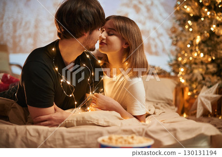 Conception of love. Beautiful young couple indoors, celebrating new year against projector Conception of love. Beautiful young couple indoors, celebrating new year against projector 130131194