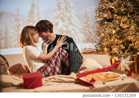 Pizza on the bed. Beautiful young couple indoors, celebrating new year against projector Pizza on the bed. Beautiful young couple indoors, celebrating new year against projector 130131209