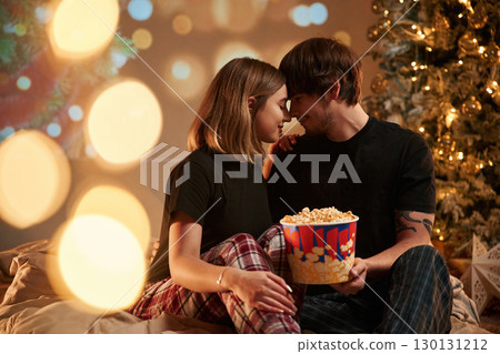 Holding popcorn. Couple celebrating New Year together 130131212