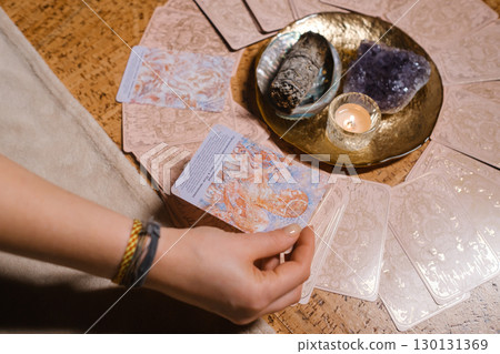 Tarot card reading session with crystals and candles on a wooden table in a cozy room during the evening 130131369