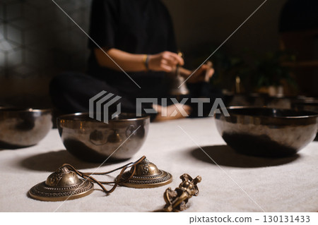 Practicing mindfulness and meditation with singing bowls in a tranquil indoor setting during a holistic wellness session Practicing mindfulness and meditation with singing bowls in a tranquil indoor setting during a holistic wellness session 130131433