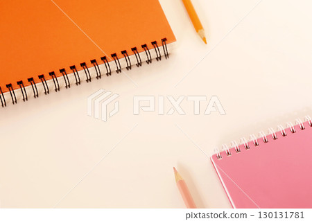 Orange and pink color pencil and spiral notebook on a white desk Orange and pink color pencil and spiral notebook on a white desk 130131781