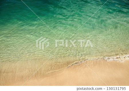 Tranquil Shoreline. A serene beach with clear green water and golden sand 130131795