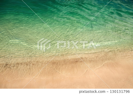 Tranquil Shoreline. A serene beach with clear green water and golden sand 130131796
