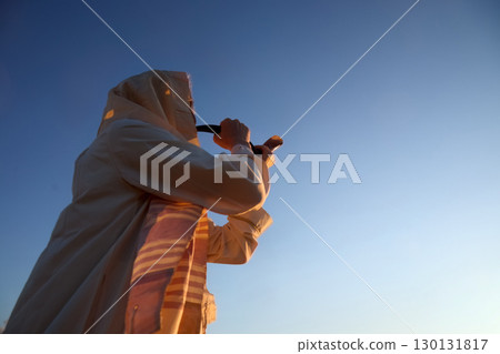 Jewish man blowing the Shofar horn of Rosh Hashanah - New Year. Tradition at Sunrise Jewish man blowing the Shofar horn of Rosh Hashanah - New Year. Tradition at Sunrise 130131817