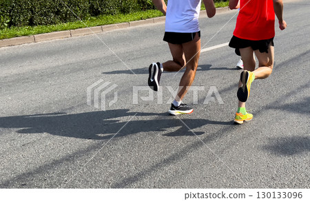 Synchronous movement two runners running city marathon on asphalt Synchronous movement two runners running city marathon on asphalt 130133096