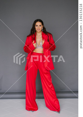 Caucasian young woman in red outfit poses for the camera, wearing a red jacket and pants Caucasian young woman in red outfit poses for the camera, wearing a red jacket and pants 130133218