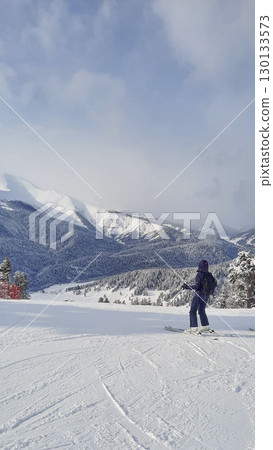 Skier admiring snowy mountain landscape on a sunny winter day. 130133573