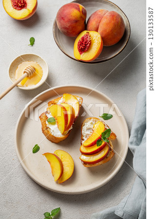 Toasted bruschetta with peach, nectarine, cream cheese or ricotta and honey on a light background Toasted bruschetta with peach, nectarine, cream cheese or ricotta and honey on a light background 130133587