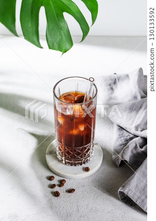 Cold brew coffee tonic in a glass with ice on a light background with coffee beans 130133592