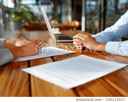 Business meeting and contract signing discussion with documents and laptop on wooden table 130133917