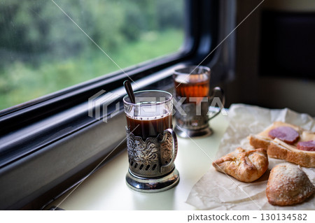 Hot tea and sandwiches pastry on train table in car. Window seat in travel, lunch break in travel Hot tea and sandwiches pastry on train table in car. Window seat in travel, lunch break in travel 130134582