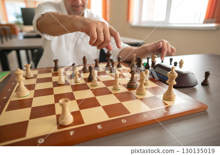 Close up of hands of middle aged caucasian man playing chess. Close up of hands of middle aged caucasian man playing chess. 130135019