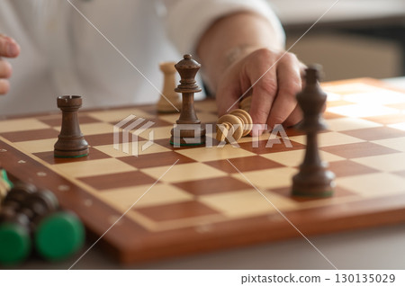 Close up of hands of middle aged caucasian man playing chess.  130135029