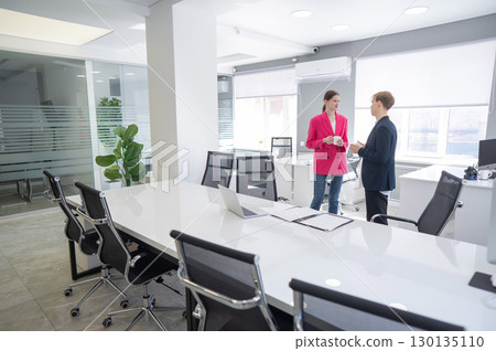 Colleagues sit drinking coffee and talking during a break at work.  130135110