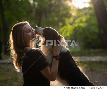 Young Caucasian woman hugging her border collie dog while walking in the park. Young Caucasian woman hugging her border collie dog while walking in the park. 130135278