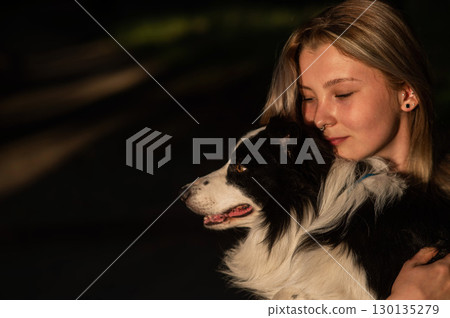 Young Caucasian woman hugging her border collie dog while walking in the park. Young Caucasian woman hugging her border collie dog while walking in the park. 130135279