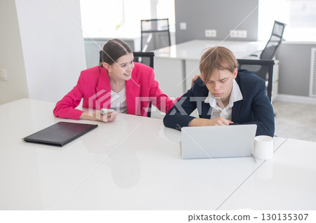 Caucasian Businesswoman Uses Smartphone While Colleague Has Problems At Work.  130135307