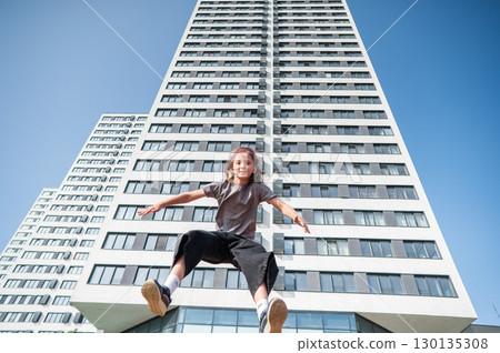 A girl jumps on an outdoor trampoline. 130135308