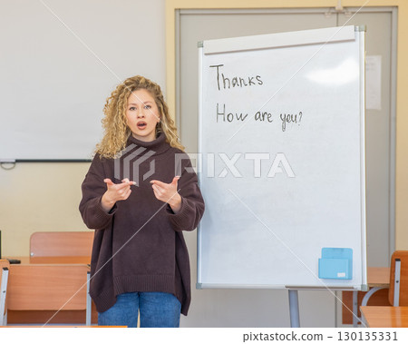 Caucasian female teacher communicates in Russian sign language with students.  130135331