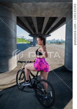 Caucasian woman in short shorts riding a bicycle.  130135343
