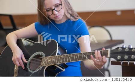 Young woman playing guitar in recording studio.  130135430